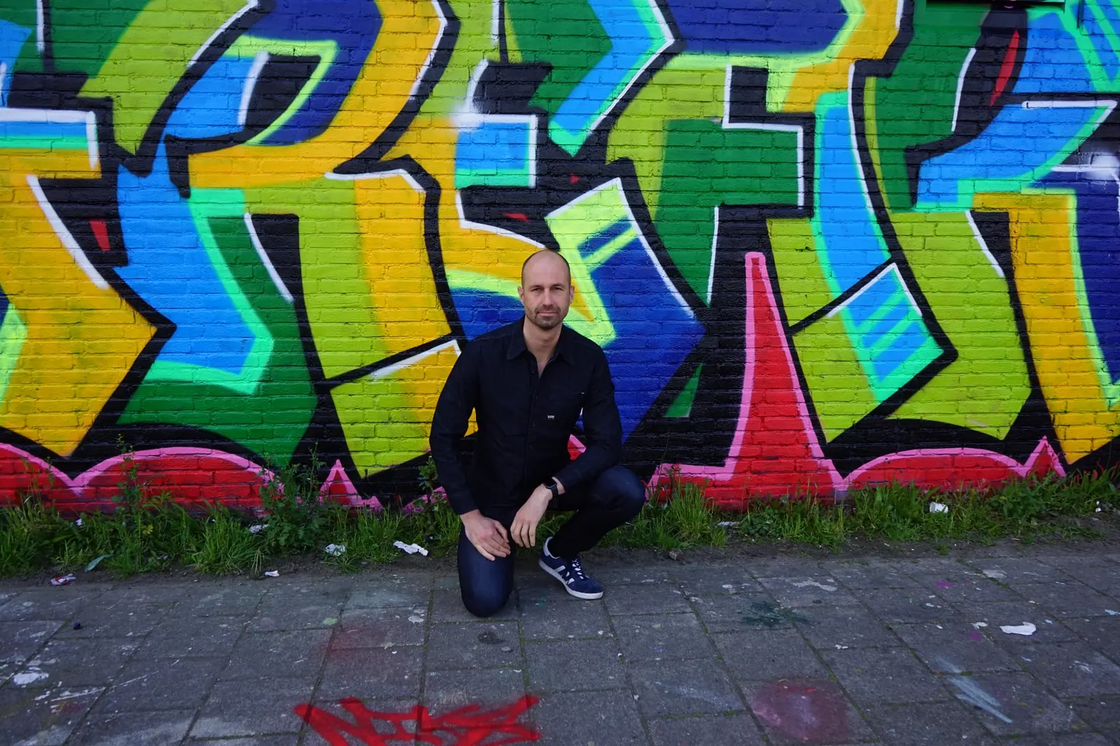 Johnny van Dyck in front of a colourful graffiti wall