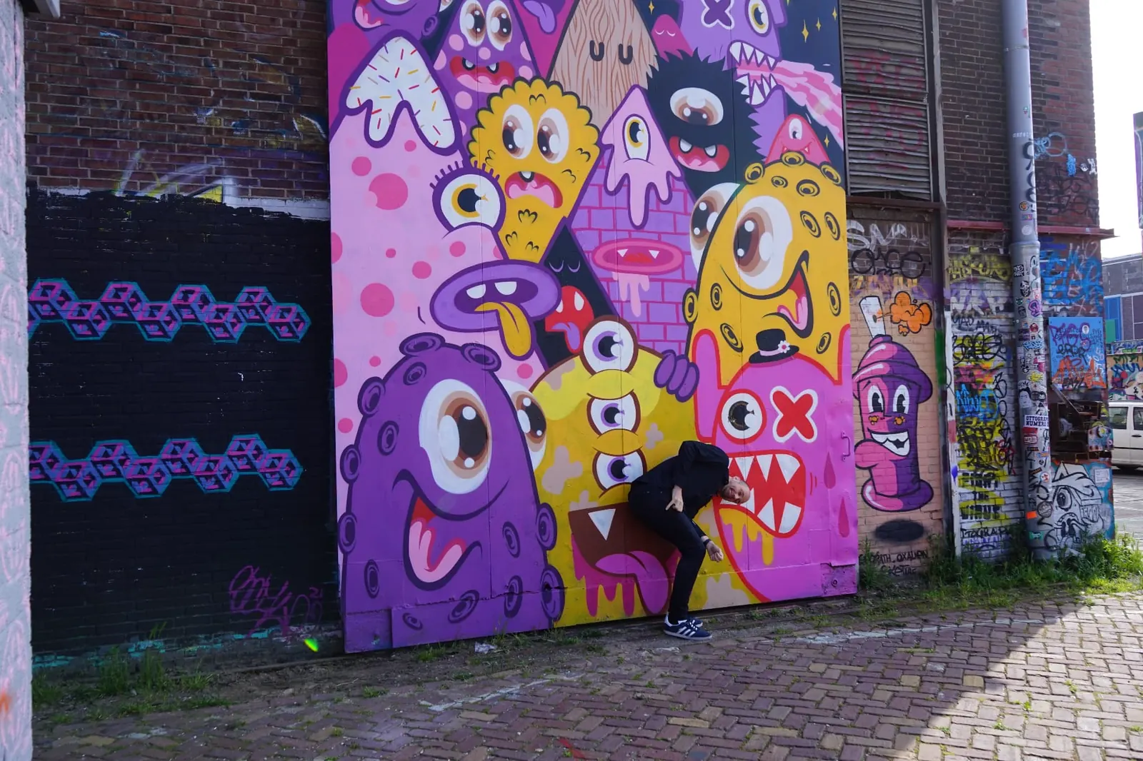 Johnny van Dyck posing at a purple street-art mural